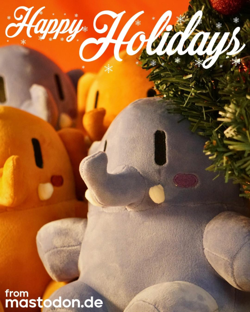 A picture of four of the new Activity Peach and Interoperability Blue Mastodon plushies next to a decorated tree with the words “Happy Holiday” stylized on top and “from mastodon.de” on the bottom