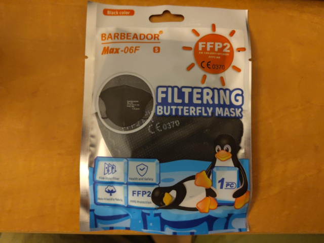image of packaging of a FFP2 butterfly mask, on the bottom part is 1 tux sleeping, and 1 tux holding a sign saying "1 pc" (referring to piece in this case)