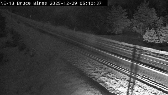 Another roadway camera shot, facing away from the village into the wilderness.  There is clearly heavy snow cover on the shoulders and down the centerline of the road, with packed or compacted snow covering the travel lanes.