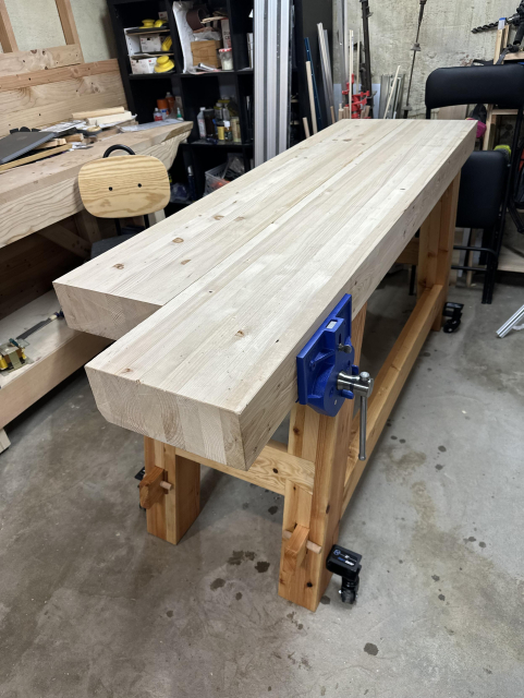 A wooden workbench with metal face vise. It is chonky: no visible parts have a dimension less than 4.5" (~115mm).