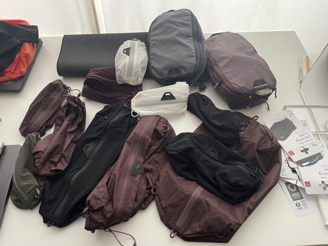 a large amount of peak design packing cubes strewn across a desk