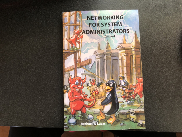 A physical copy of "Networking for System
Administrators", 2nd edition, by Michael W Lucas. The colorful cover art has a delightful illustration of penguins and daemons engaged in the various tasks of building construction.
