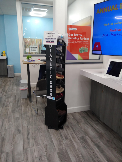 A black shoe rack in a storefront that is labled "Diabetic Shoes" in bold white lettering. There a several pairs and styles of orthopedic shoes on the rack.