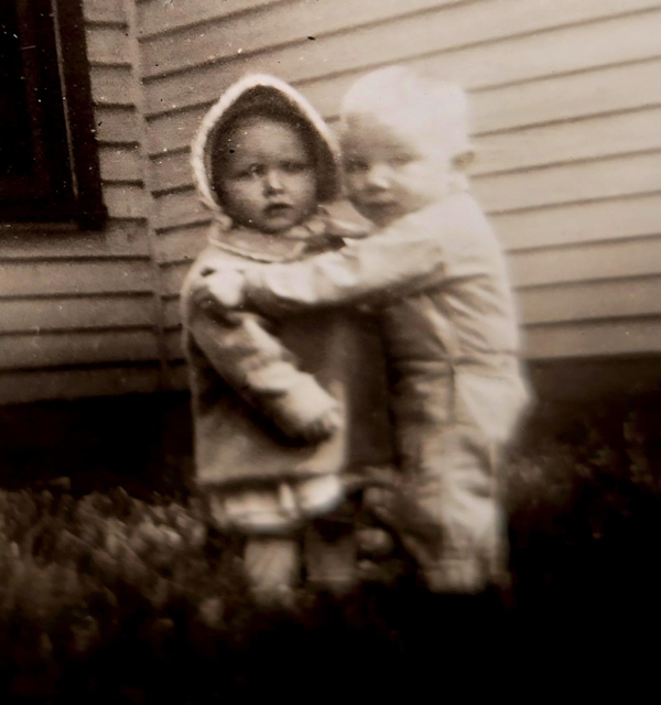 1942 black and white photo of mom and her favorite cousin, hugging and looking into camera.