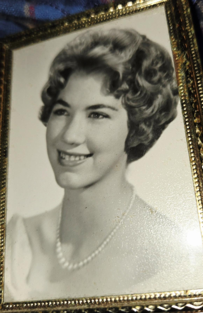 Mom, college graduation photo. Profile in black and white of a woman with short wavy hair, smiling. Traditional pearl necklace for photo.