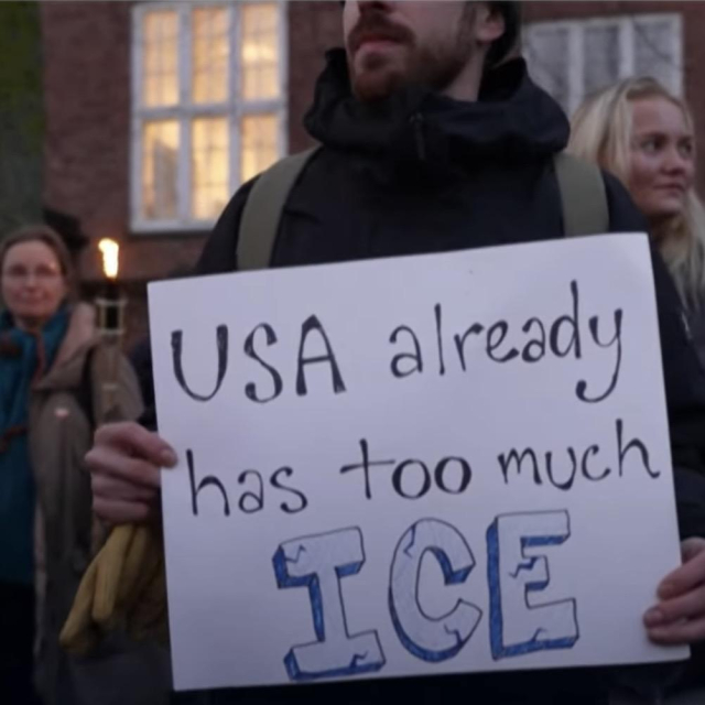 Bearded white male in winter coat holding up a protest sign with hand written letters saying: USA Already has too much ICE.