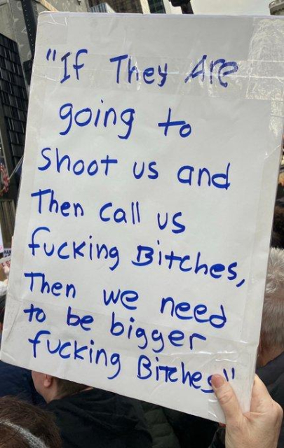 Placard reads: If they are going to shoot us an then call us "fucking bitches," then we need to be bigger fucking bitches. 