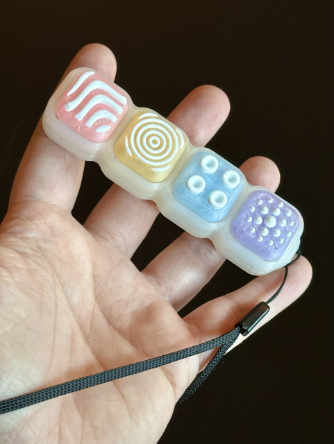 Rainbow coloured keyboard fidget toy with wrist strap. 