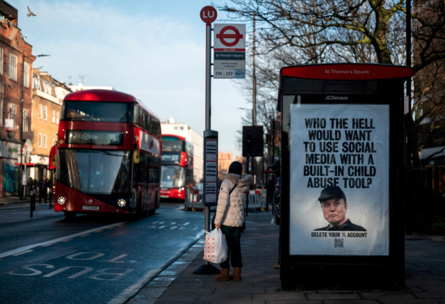 Bus shelter in London, shows an ad with Elon Musk on it and says "WHO THE HELL WOULD WANT TO USE SOCIAL MEDIA WITH A BUILD-IN CHILD ABUSE TOOL?"
