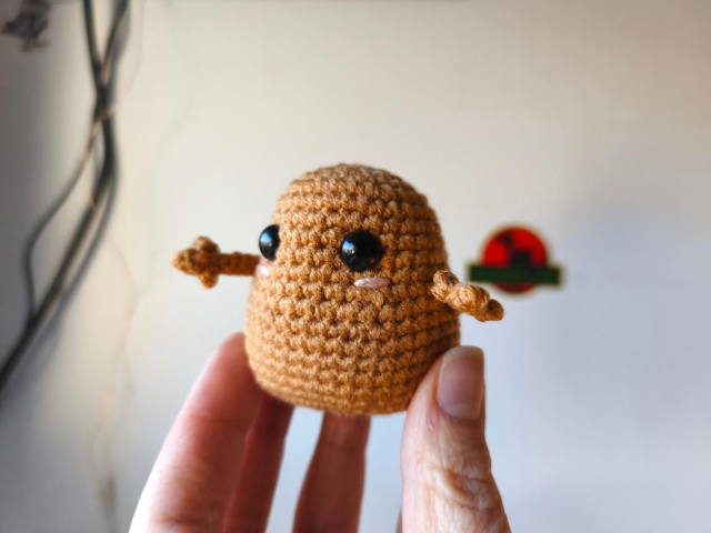 Patata pequeña simpaticona con mejillas rosadas y manitas abiertas. Tejida a crochet
