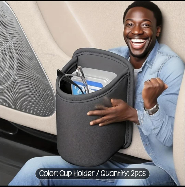 An extremely happy black man is sitting in the door pocket of a car. Because for some reason, he's really tiny. And he's holding a cup holder which is the thing that's for sale. But the cup holder is now so big that he would fit in it if you wanted him to. There's a pair of glasses in it. They are the size of him. I can't stress enough.He's supposed to be an actual human.And he's incredibly happy like so happy you've never seen anyone so happy to see a cup holder.He also has two left hands.
