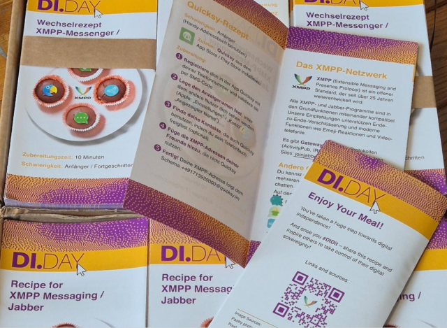 Mehrere gedruckte Faltblätter und Karten zum Thema **XMPP/Jabber** liegen aufgefächert in einer Schachtel. Überschriften wie „Wechselrezept XMPP-Messenger“, „Recipe for XMPP Messaging“ und „Enjoy Your Meal!“; farbiges Design (Gelb/Lila), Icons, kurze Erklärtexte und ein QR-Code. Foto: GeOrG (vermutlich cc by)