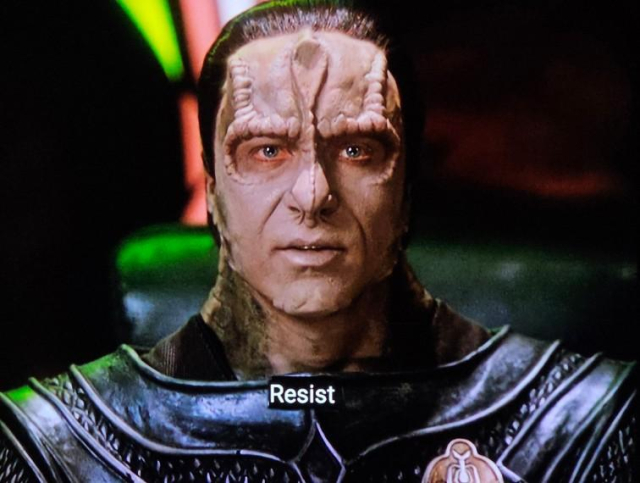 Star Trek Deep Space Nine scene. And in case you never gave it a fair shake, DS9 is absolutely the real deal good shit. Ok, so here we see a fella named Damar. He's a Cardassian with a "C" not the other ones. He's got a boney ridgey facial structure because he's not human, with spiney features on his face and forehead and around his eyes. And a mega thicc neck too. He's wearing a military shell type armour outfit that also looks hard and tough. He's addressing the camera, as if he's making some kind of announcement. It's 3 screenshots but the visual is all the same. Damar looking serious as a heart attack. Closed caption reads, "RESIST. RESIST TODAY. RESIST TOMORROW."

(Also, in case you were wondering, FUCK ICE)