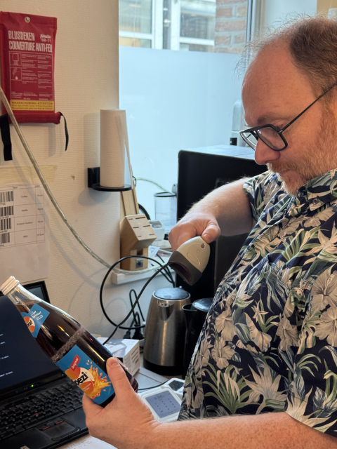 A picture of a man scanning a Spezi bottle with a barcode scanner