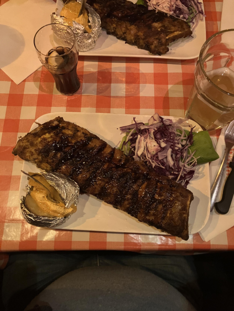 A rack of spare ribs, a salad of red cabbage, and a curried baked potato on a plate at Amedeo in Brussels