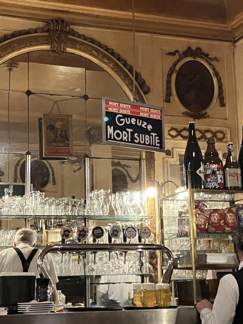 A sign on top of a well stocked bar saying “Gueueze Mort Subite”