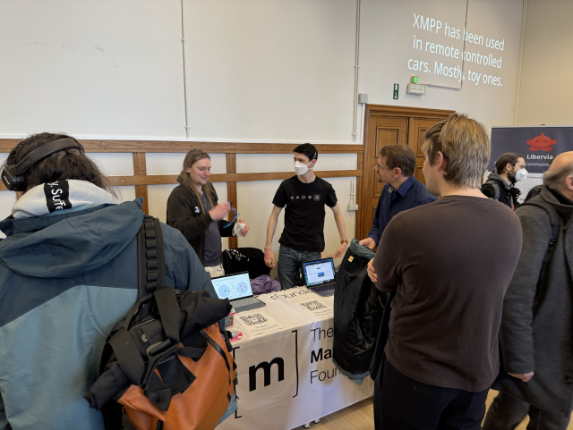 A photo of the matrix booth. It is crowded, and the booth only has laptops and stickers left. There are no t-shirts anymore.
