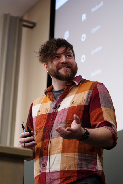 A portrait of Cassidy, a man wearing a shirt and smiling at somebody off frame