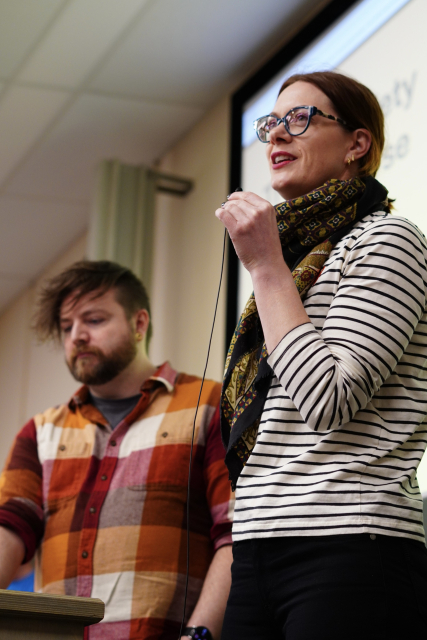 A picture of Anne, a woman speaking and smiling to the audience. In the background we can also see Cassidy