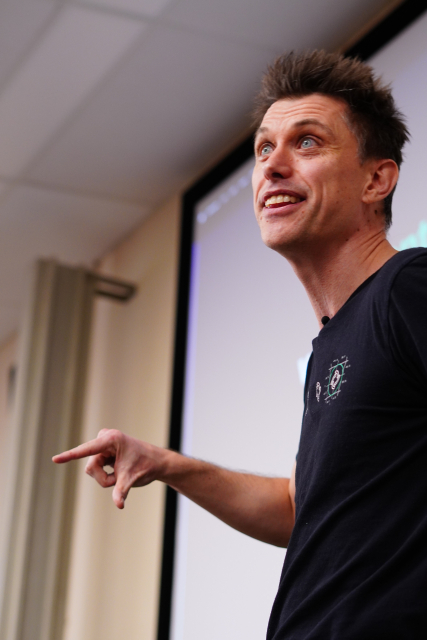 A close portrait of Neil, smiling and taking to the audience