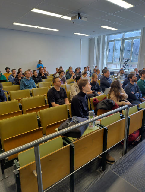 A ulb room with people listening to a speaker 
