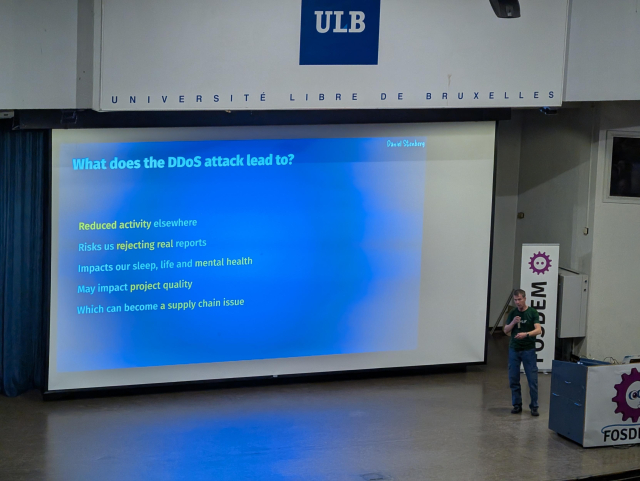 The creator of curl standing in front of a projector screen that reads

What does the DDoS attack lead to?
- Reduced activity elsewhere
- Risks us rejecting real reports
- Impacts our sleep, life and mental health
- May impact project quality
- Which can become a supply chain issue