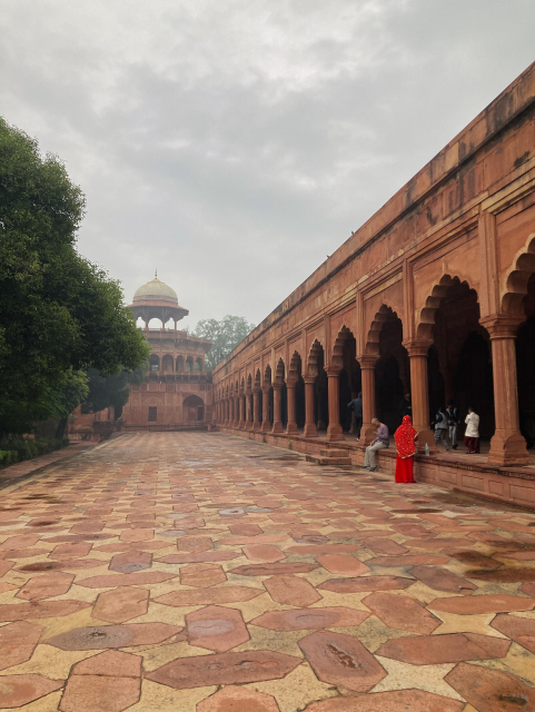 The red marble side of Taj Mahal entrance, India.we can see a figure draped in red.