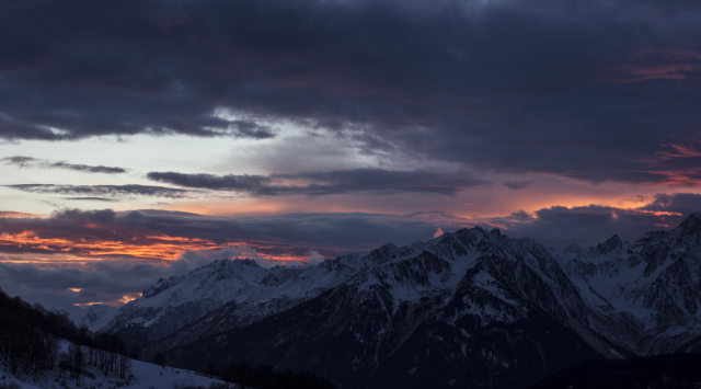 alps mountains after sunset, so we see the sun lensing and lighting the clouds from below